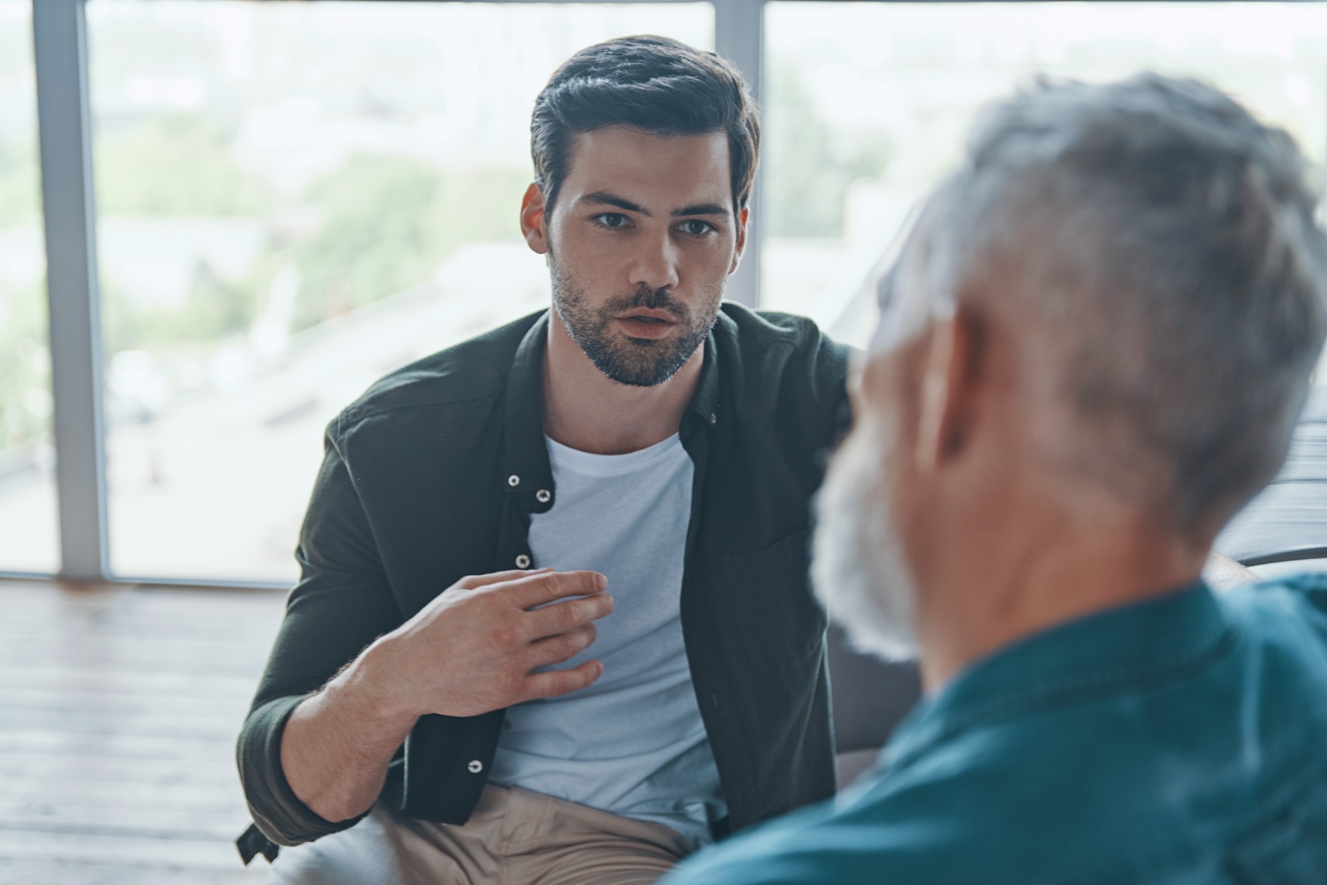 Handsome young man talking to his senior father
